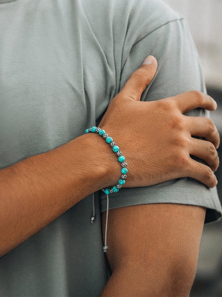 Person wearing a turquoise beaded bracelet on a blurred background